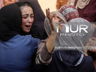 Mourners weep near the bodies of Palestinians killed in an Israeli airstrike amid the conflict between Israel and Hamas in Deir al-Balah, ce...