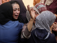 Mourners weep near the bodies of Palestinians killed in an Israeli airstrike amid the conflict between Israel and Hamas in Deir al-Balah, ce...