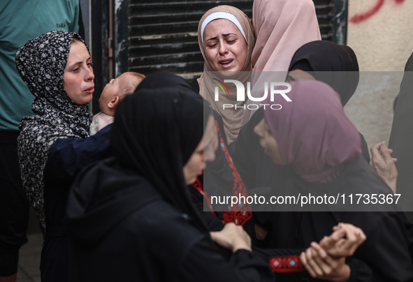 Mourners weep near the bodies of Palestinians killed in an Israeli airstrike amid the conflict between Israel and Hamas in Deir al-Balah, ce...