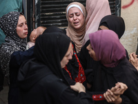 Mourners weep near the bodies of Palestinians killed in an Israeli airstrike amid the conflict between Israel and Hamas in Deir al-Balah, ce...