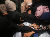 Mourners gather around the bodies of Palestinians killed in an Israeli strike amid the Israel-Hamas conflict in Deir Al-Balah, in the centra...