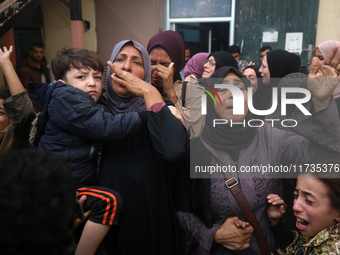 Mourners weep near the bodies of Palestinians killed in an Israeli airstrike amid the conflict between Israel and Hamas in Deir al-Balah, ce...