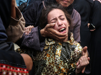 Mourners weep near the bodies of Palestinians killed in an Israeli airstrike amid the conflict between Israel and Hamas in Deir al-Balah, ce...