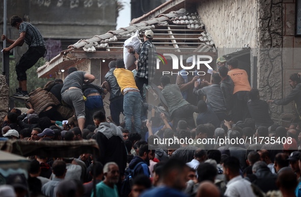 Palestinians scramble to receive sacks of flour at a United Nations Relief and Works Agency (UNRWA) aid distribution center amid the Israel-...