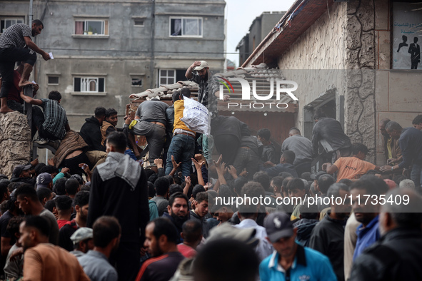 Palestinians scramble to receive sacks of flour at a United Nations Relief and Works Agency (UNRWA) aid distribution center amid the Israel-...