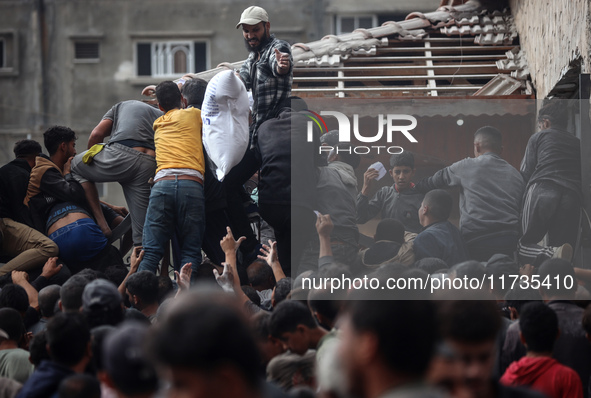 Palestinians scramble to receive sacks of flour at a United Nations Relief and Works Agency (UNRWA) aid distribution center amid the Israel-...