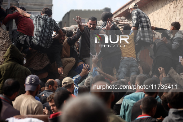 Palestinians scramble to receive sacks of flour at a United Nations Relief and Works Agency (UNRWA) aid distribution center amid the Israel-...