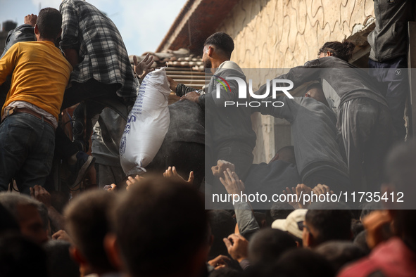 Palestinians scramble to receive sacks of flour at a United Nations Relief and Works Agency (UNRWA) aid distribution center amid the Israel-...