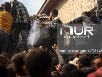 Palestinians scramble to receive sacks of flour at a United Nations Relief and Works Agency (UNRWA) aid distribution center amid the Israel-...