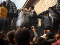 Palestinians scramble to receive sacks of flour at a United Nations Relief and Works Agency (UNRWA) aid distribution center amid the Israel-...