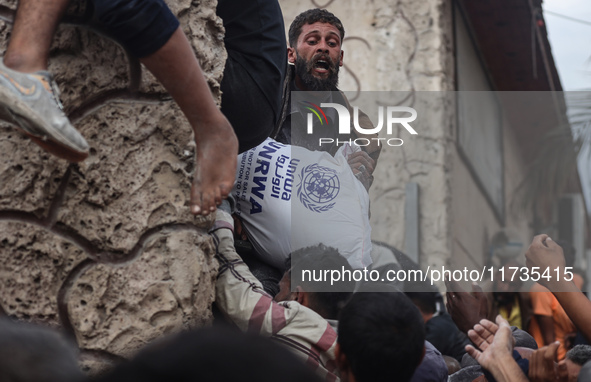 Palestinians scramble to receive sacks of flour at a United Nations Relief and Works Agency (UNRWA) aid distribution center amid the Israel-...