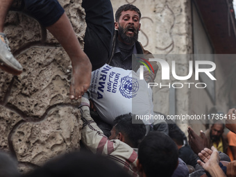 Palestinians scramble to receive sacks of flour at a United Nations Relief and Works Agency (UNRWA) aid distribution center amid the Israel-...