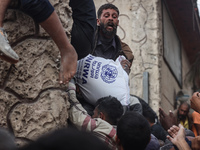 Palestinians scramble to receive sacks of flour at a United Nations Relief and Works Agency (UNRWA) aid distribution center amid the Israel-...