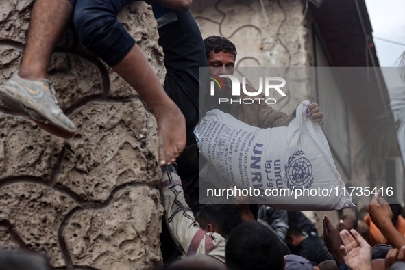 Palestinians scramble to receive sacks of flour at a United Nations Relief and Works Agency (UNRWA) aid distribution center amid the Israel-...