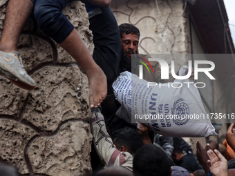 Palestinians scramble to receive sacks of flour at a United Nations Relief and Works Agency (UNRWA) aid distribution center amid the Israel-...