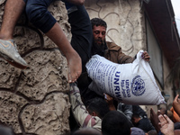 Palestinians scramble to receive sacks of flour at a United Nations Relief and Works Agency (UNRWA) aid distribution center amid the Israel-...