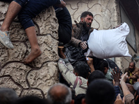 Palestinians scramble to receive sacks of flour at a United Nations Relief and Works Agency (UNRWA) aid distribution center amid the Israel-...