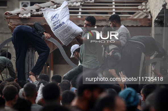 Palestinians scramble to receive sacks of flour at a United Nations Relief and Works Agency (UNRWA) aid distribution center amid the Israel-...