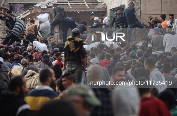 Palestinians scramble to receive sacks of flour at a United Nations Relief and Works Agency (UNRWA) aid distribution center amid the Israel-...