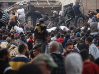 Palestinians scramble to receive sacks of flour at a United Nations Relief and Works Agency (UNRWA) aid distribution center amid the Israel-...