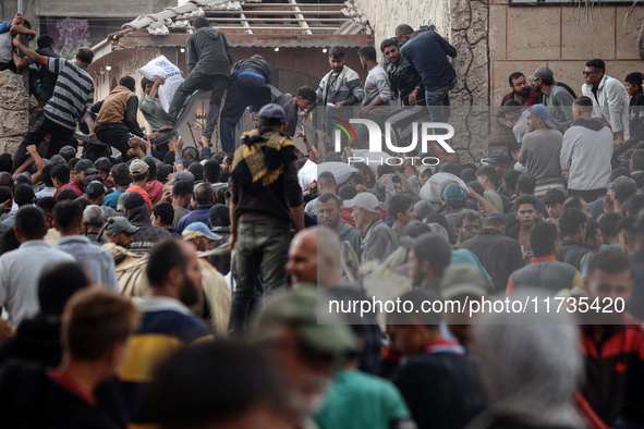 Palestinians scramble to receive sacks of flour at a United Nations Relief and Works Agency (UNRWA) aid distribution center amid the Israel-...