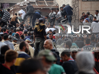 Palestinians scramble to receive sacks of flour at a United Nations Relief and Works Agency (UNRWA) aid distribution center amid the Israel-...