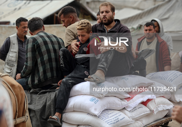 People receive bags of flour distributed by a United Nations aid organization in Deir Al-Balah, in the central Gaza Strip, on November 3, 20...