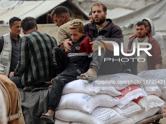 People receive bags of flour distributed by a United Nations aid organization in Deir Al-Balah, in the central Gaza Strip, on November 3, 20...