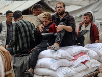 People receive bags of flour distributed by a United Nations aid organization in Deir Al-Balah, in the central Gaza Strip, on November 3, 20...