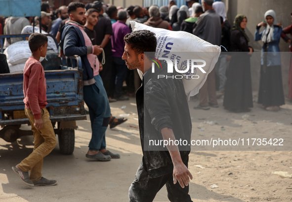 People receive bags of flour distributed by a United Nations aid organization in Deir Al-Balah, in the central Gaza Strip, on November 3, 20...