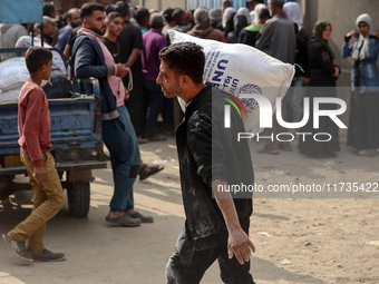 People receive bags of flour distributed by a United Nations aid organization in Deir Al-Balah, in the central Gaza Strip, on November 3, 20...