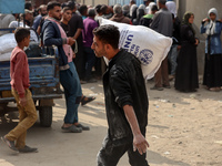 People receive bags of flour distributed by a United Nations aid organization in Deir Al-Balah, in the central Gaza Strip, on November 3, 20...