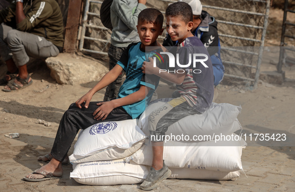 People receive bags of flour distributed by a United Nations aid organization in Deir Al-Balah, in the central Gaza Strip, on November 3, 20...