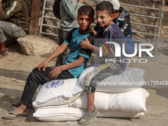 People receive bags of flour distributed by a United Nations aid organization in Deir Al-Balah, in the central Gaza Strip, on November 3, 20...