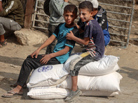 People receive bags of flour distributed by a United Nations aid organization in Deir Al-Balah, in the central Gaza Strip, on November 3, 20...