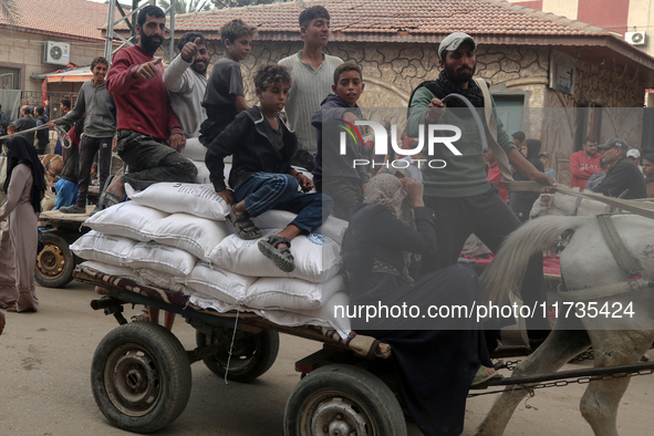 People receive bags of flour distributed by a United Nations aid organization in Deir Al-Balah, in the central Gaza Strip, on November 3, 20...