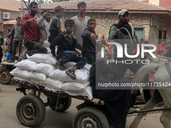 People receive bags of flour distributed by a United Nations aid organization in Deir Al-Balah, in the central Gaza Strip, on November 3, 20...