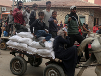 People receive bags of flour distributed by a United Nations aid organization in Deir Al-Balah, in the central Gaza Strip, on November 3, 20...