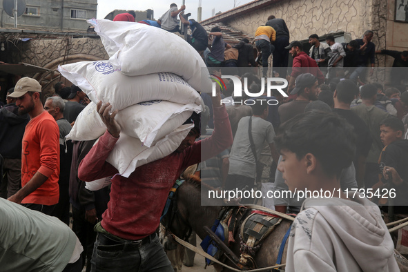 People receive bags of flour distributed by a United Nations aid organization in Deir Al-Balah, in the central Gaza Strip, on November 3, 20...