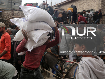 People receive bags of flour distributed by a United Nations aid organization in Deir Al-Balah, in the central Gaza Strip, on November 3, 20...