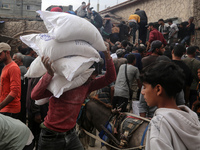 People receive bags of flour distributed by a United Nations aid organization in Deir Al-Balah, in the central Gaza Strip, on November 3, 20...