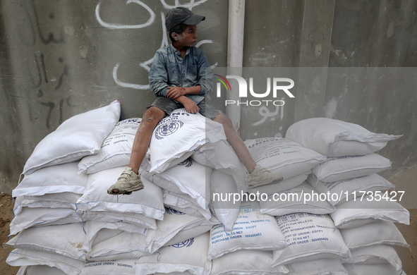 A Palestinian boy sits on top of sacks of flour at a United Nations Relief and Works Agency (UNRWA) aid distribution center amid the Israel-...