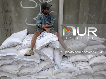 A Palestinian boy sits on top of sacks of flour at a United Nations Relief and Works Agency (UNRWA) aid distribution center amid the Israel-...