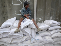 A Palestinian boy sits on top of sacks of flour at a United Nations Relief and Works Agency (UNRWA) aid distribution center amid the Israel-...