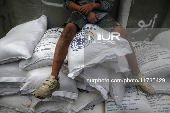 A Palestinian boy sits on top of sacks of flour at a United Nations Relief and Works Agency (UNRWA) aid distribution center amid the Israel-...