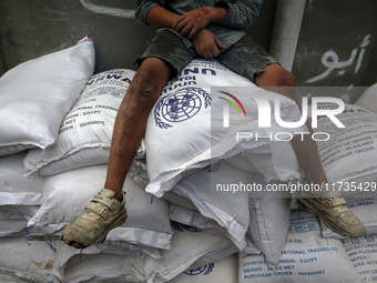 A Palestinian boy sits on top of sacks of flour at a United Nations Relief and Works Agency (UNRWA) aid distribution center amid the Israel-...