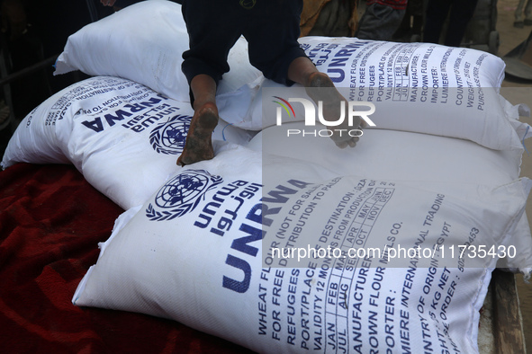 A Palestinian boy sits on top of sacks of flour at a United Nations Relief and Works Agency (UNRWA) aid distribution center amid the Israel-...