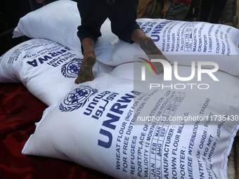 A Palestinian boy sits on top of sacks of flour at a United Nations Relief and Works Agency (UNRWA) aid distribution center amid the Israel-...