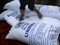 A Palestinian boy sits on top of sacks of flour at a United Nations Relief and Works Agency (UNRWA) aid distribution center amid the Israel-...