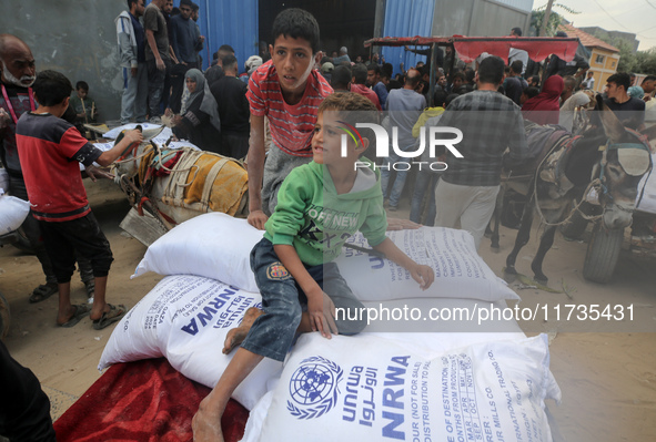 A Palestinian boy sits on top of sacks of flour at a United Nations Relief and Works Agency (UNRWA) aid distribution center amid the Israel-...